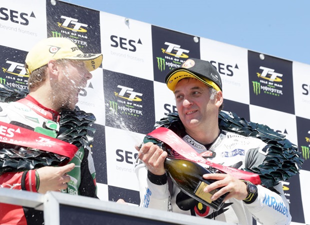 Michael Rutter sprays champagne into second placed Daley Mathison's mouth on the SES TT Zero Race podium. Photo Stephen Davison / Pacemaker Press Intl
