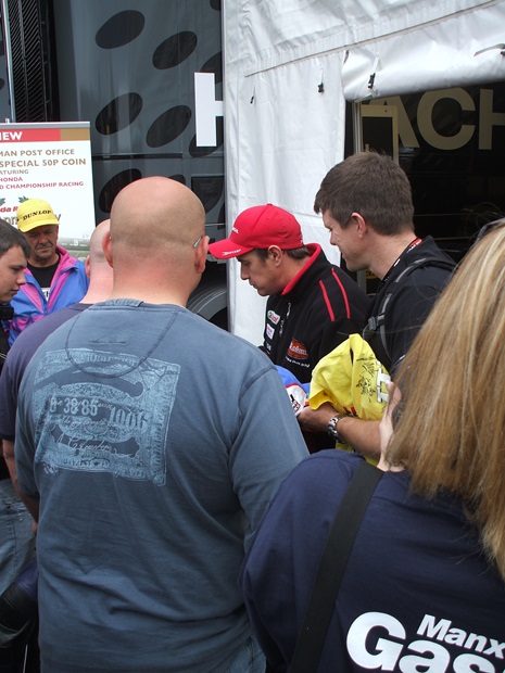 15-times TT winner John McGuinness signs autographs during Wednesday's rain delay