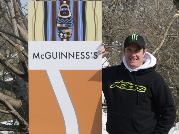 19-times Isle of Man TT winner John McGuinness with the sign announcing a corner now bears his name